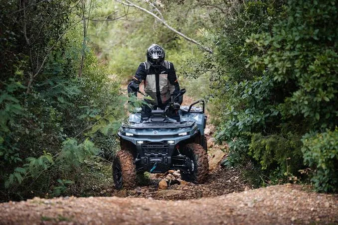 Sivi CFMOTO C4 Touring na kamenitoj šumskoj stazi